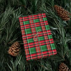 a green and red plaid wrapping paper on top of pine cones