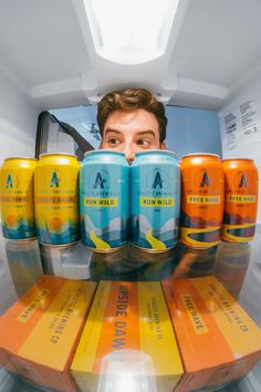 a man is hiding in the refrigerator with six cans of beer on top of it