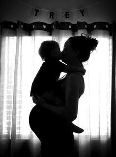 a woman holding a baby in front of a window with the word trey on it