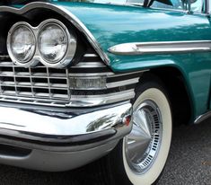 the front end of an old green car with chrome rims and grill grilles