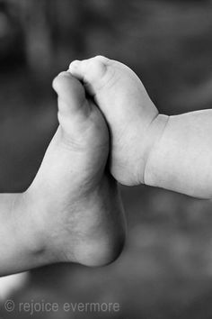 a black and white photo of a baby's foot being held in the air