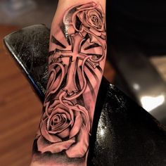 a person with a cross and roses tattoo on their arm