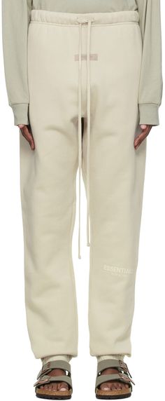 Straight-leg cotton-blend fleece lounge pants in beige. Logo flocked in off-white at leg. · Mid-rise · Rib knit gusset at dropped inseam · Two-pocket styling · Drawstring at elasticized waistband · Rubberized logo patch at front · Elasticized cuffs Please note that this item may not be shipped within the EU. Supplier color: Wheat Cozy Beige Cotton Sweatpants, Beige Cotton Sweatpants For Winter, Cozy Beige Cotton Pants, Cream Cotton Sweatpants For Fall, Neutral Cotton Loungewear Pants, Neutral Sweatpants For Fall Loungewear, Fear Of God Essentials, Trouser Pants Women, Fear Of God