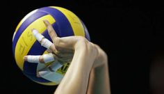 a woman holding a volleyball in her right hand and making the peace sign with her left hand