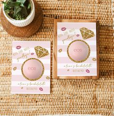 two cards with pink and gold foil on them sitting next to a potted plant