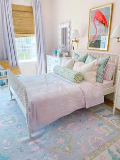 a bedroom decorated in pastel colors with pink flamingos on the bed and blue rug