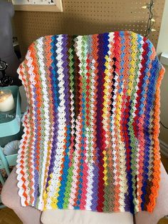 a multicolored crocheted blanket sitting on top of a chair next to a wall