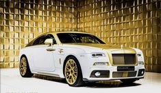 a white and gold rolls royce parked in front of a golden wall