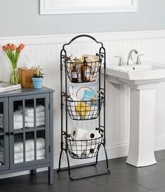 a bathroom with a sink and two baskets on the stand next to it, all filled with toiletries