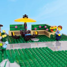 a lego set is shown with people sitting at tables and umbrellas in the background