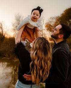 a man holding a baby up in the air while standing next to a woman and child