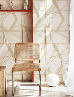 a wooden chair sitting in front of a wall with decorative designs on it's walls