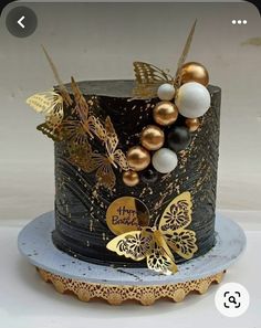 a black and gold birthday cake decorated with butterflies