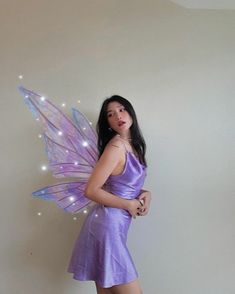 a woman in a purple dress with a fairy wings on her back, posing for the camera