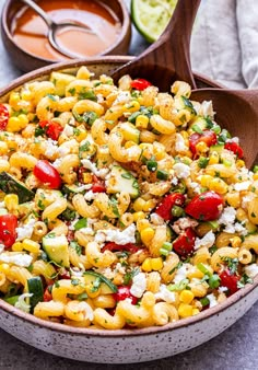 a bowl full of pasta salad with tomatoes, cucumbers and feta cheese