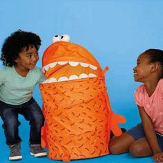 two children are playing with an orange monster