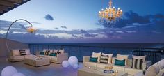 a living room filled with lots of furniture on top of a wooden floor next to the ocean