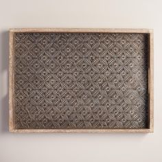 a wooden tray with an intricate design on the bottom and sides, hanging from a wall