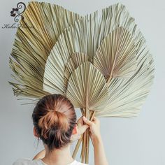 a woman is holding up a large fan