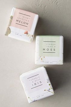 three soap bars sitting next to each other on top of a white surface with pink and green flowers