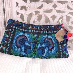 a blue and green purse sitting on top of a white bed next to a wall