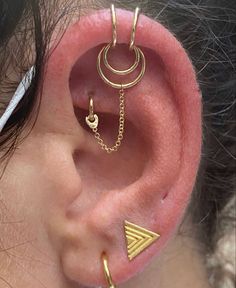 a woman wearing gold ear piercings with chains on the back of her ear and an arrow