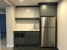 an empty kitchen with stainless steel appliances and gray cabinets, along with dark tile flooring