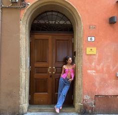 a woman standing in front of a brown door