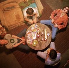 three people sitting around a table with food on it