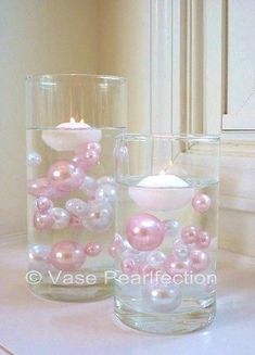 three glass vases with pearls and candles in them