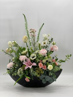 a black bowl filled with flowers and greenery