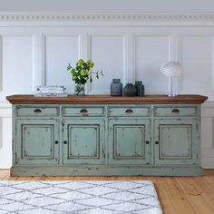 an old green cabinet in a white room with a rug on the floor next to it