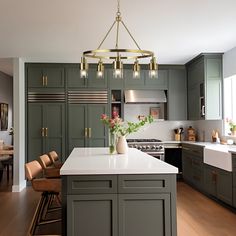 a large kitchen with green cabinets and white counter tops, an island in the middle