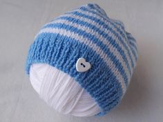 a blue and white knitted hat with a button on the front, sitting on a white surface