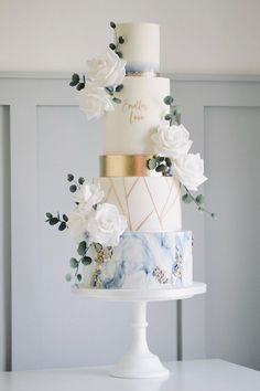 a three tiered wedding cake with white flowers and greenery