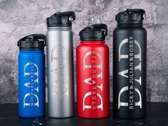 three water bottles sitting next to each other on top of a black table with white writing