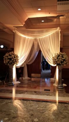 an elegant wedding setup with white drapes and flowers