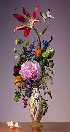 a vase filled with lots of flowers on top of a wooden table next to a butterfly