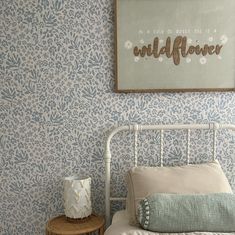 a white bed sitting next to a wall with blue flowers on it