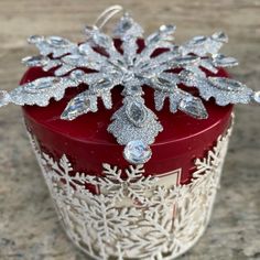 a red candle with silver snowflakes on it sitting on top of a table