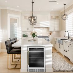 a kitchen with white cabinets and an island in the middle, surrounded by black chairs