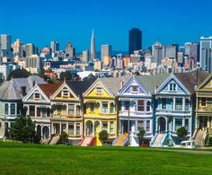 the painted houses in san francisco, california are all different colors and shapes with city buildings in the background