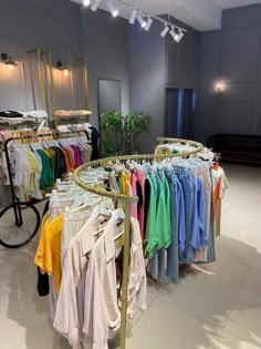 a clothing rack with shirts hanging on it's sides in a room next to a bike