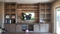 a living room with built in bookshelves and a television mounted on the wall