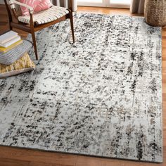 a white rug with black and grey designs on it in front of a wooden chair