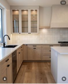 a kitchen with wooden floors and white counter tops next to a large window in the corner