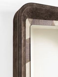 a mirror that is on the wall with a brown frame and some white walls behind it