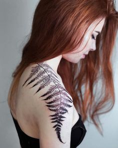 a woman with red hair has a fern tattoo on her upper arm and back shoulder