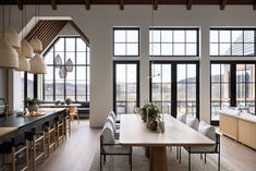 a large dining room with lots of windows next to a kitchen table and counter top