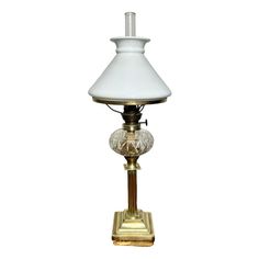 an antique brass table lamp with a white glass shade on the base and a gold plated metal base